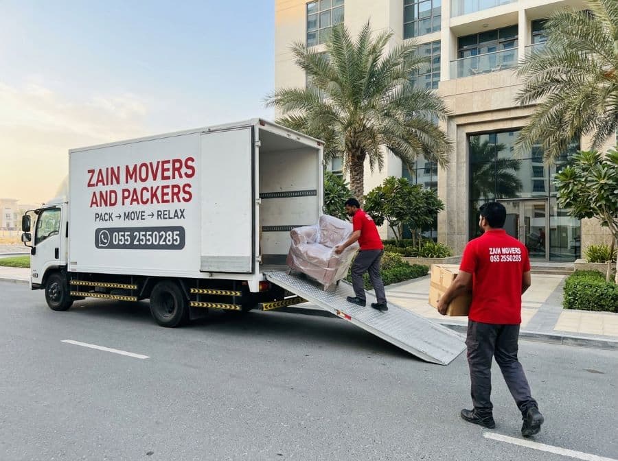 Zain Movers crew unloading a branded truck outside an Abu Dhabi residential tower