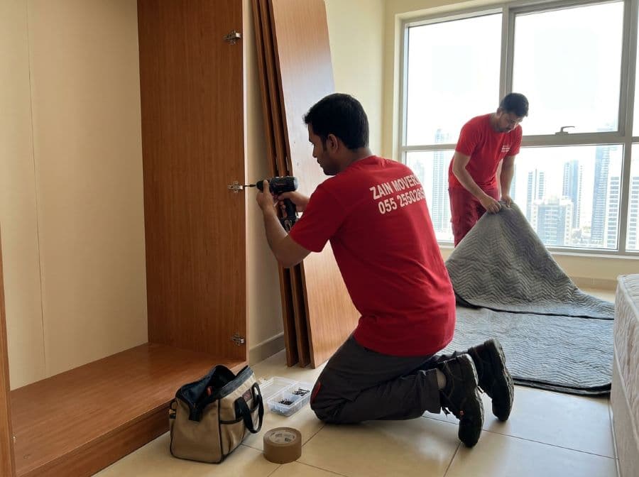 Zain Movers carpenter dismantling a large wardrobe in an Al Ain bedroom