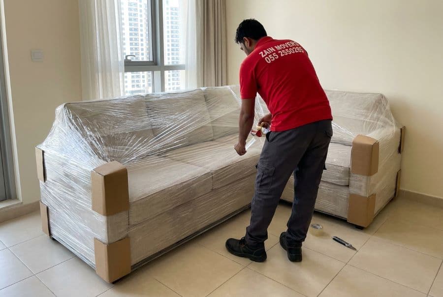 Sofa wrapped in stretch film and corner guards before loading by Zain Movers in Al Ain