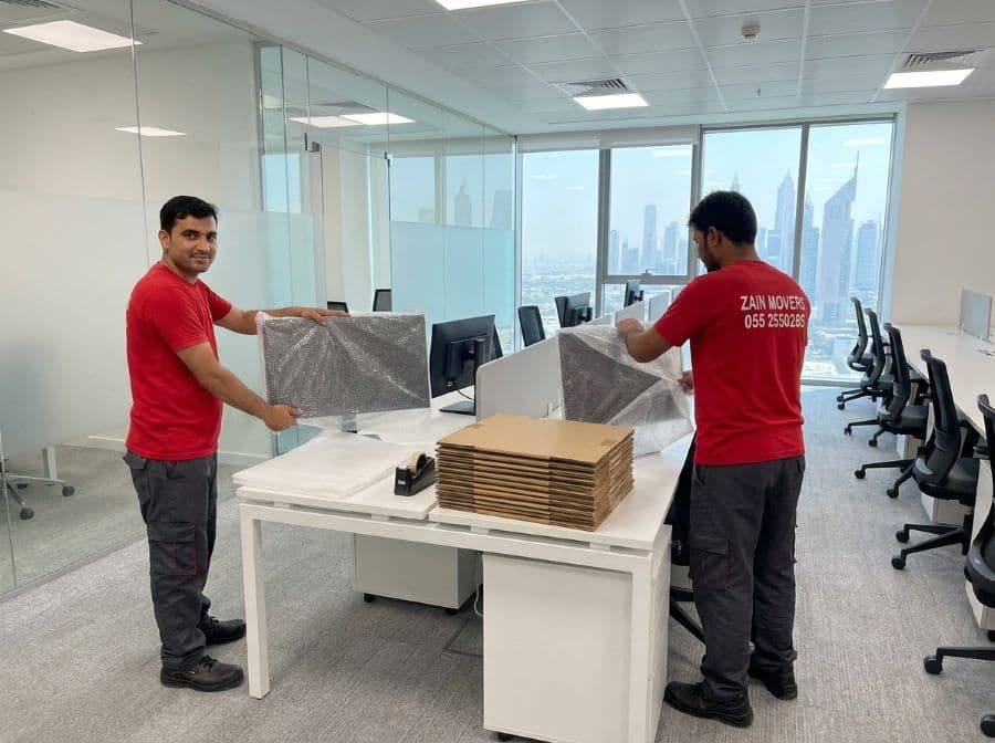 Zain Movers crew wrapping office monitors and workstations during an office relocation in Dubai