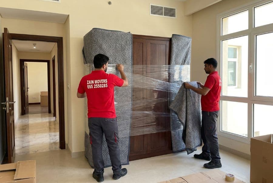 Movers wrapping an oversized wardrobe before loading it from a Dubai villa