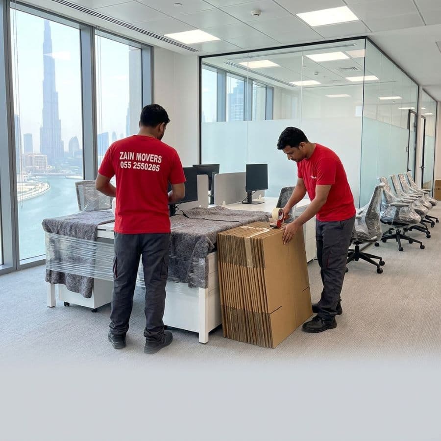 Zain Movers crew wrapping office furniture inside a Business Bay tower